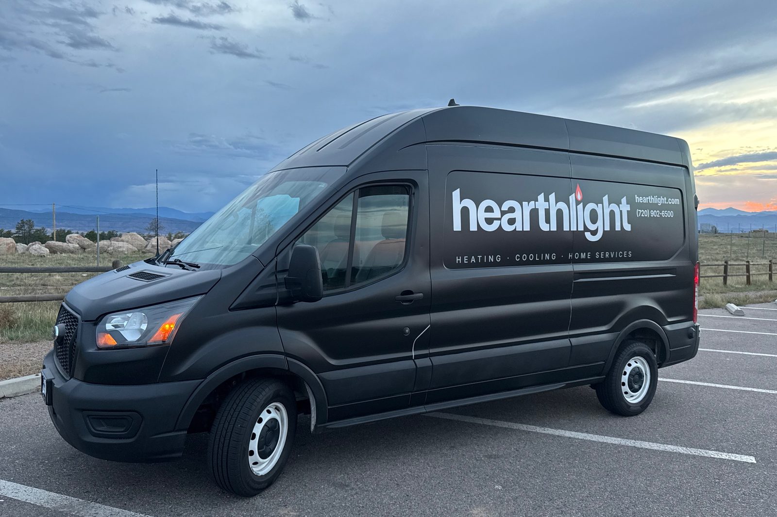 The Hearthlight van - satin black Ford Transit, wrapped - parked at sunset in Douglas County